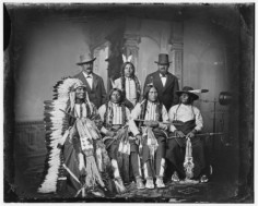Grupa Siuksów. Wśród nich słynni Cętkowany Ogon (stoi) i Wielki Mały Człowiek (siedzi obok olbrzyma Dotyka Chmur). Zdjęcie pochodzi z 1875 roku.